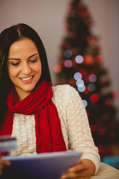 Jolie brune, magasinage en ligne avec tablette à Noël