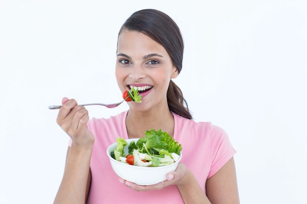 Jolie brune mangeant un bol de salade