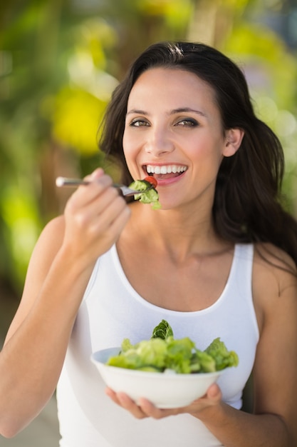 Jolie brune mangeant un bol de salade