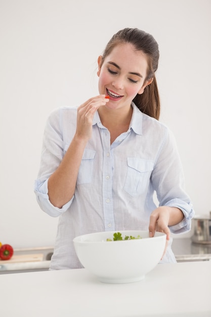 Jolie brune mangeant un bol de salade