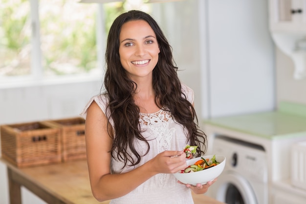 Jolie brune mangeant une salade