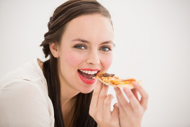 Jolie brune, manger une tranche de pizza