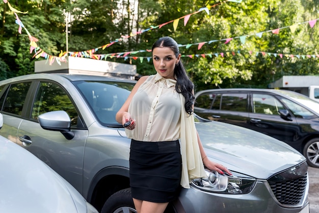 Jolie brune offrant la clé de la nouvelle voiture