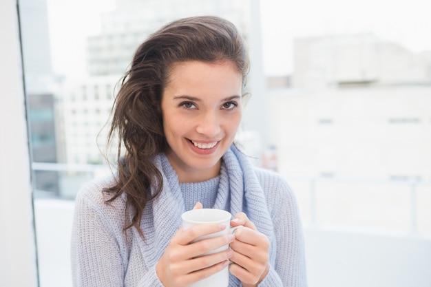 Jolie brune prenant un café près de la fenêtre