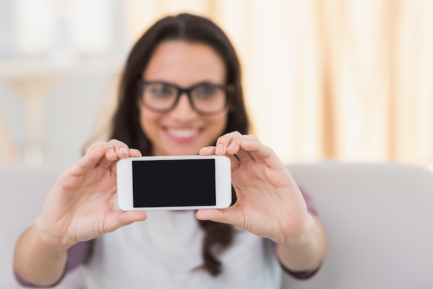 Jolie brune prenant un selfie sur le canapé