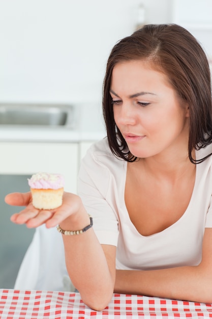 Jolie brune en regardant un petit gâteau