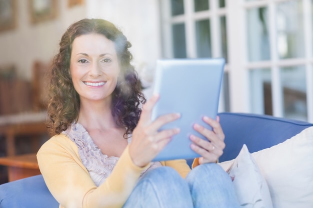 Jolie brune se détendre sur le canapé avec tablette