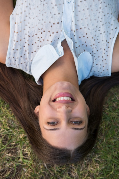 Jolie brune souriante à la caméra sur l&#39;herbe