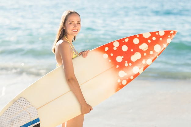 Jolie brune tenant la planche de surf