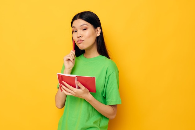 Jolie brune Tshirts vert avec carnet rouge et stylo fond jaune inaltéré