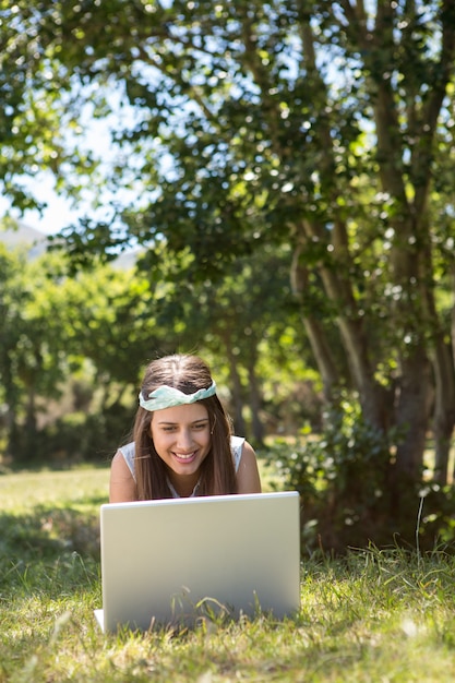 Jolie brune utilisant un ordinateur portable dans le parc