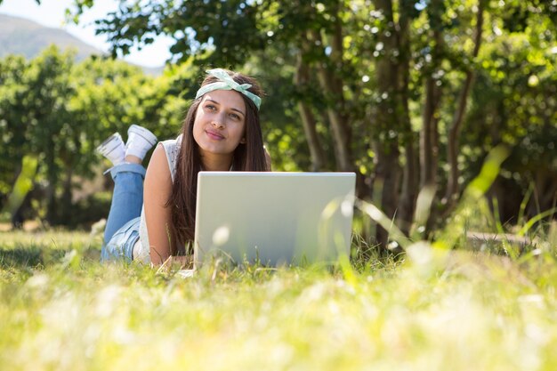 Jolie brune utilisant un ordinateur portable dans le parc