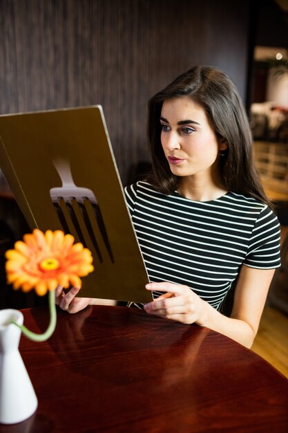 Jolie brune vérifiant le menu au bar