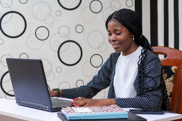 Jolie dame africaine se sentant heureuse alors qu'elle travaille au bureau