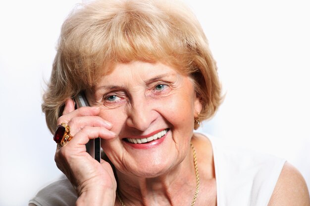 une jolie dame senior parlant au téléphone sur fond blanc