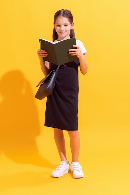 Jolie écolière portant l'uniforme scolaire moderne isolé sur fond jaune concept de