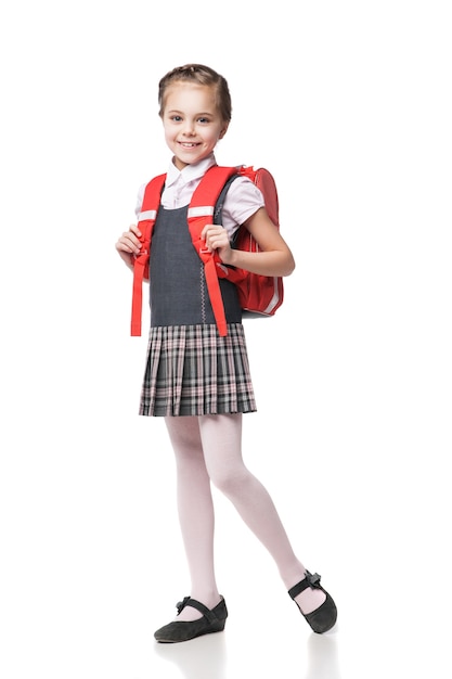 Jolie écolière souriante en uniforme debout sur fond blanc