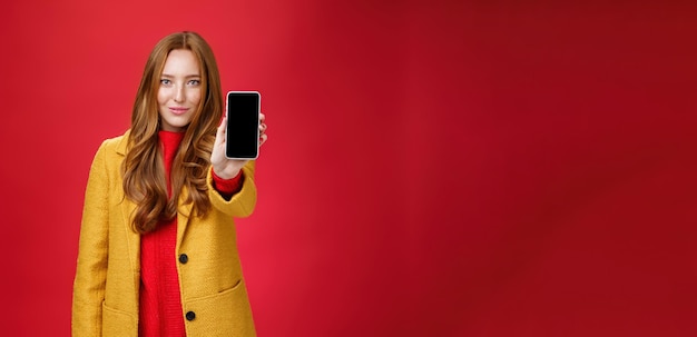 Photo jolie et élégante fille au gingembre avec un regard confiant et un sourire assuré tirant sur un téléphone portable