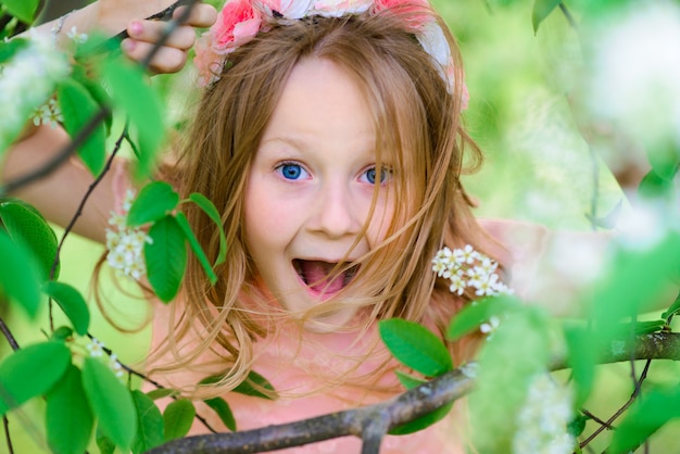 Jolie enfant fille souriante et jouant dans les fleurs du jardin, arbres en fleurs, cerise, pommes.