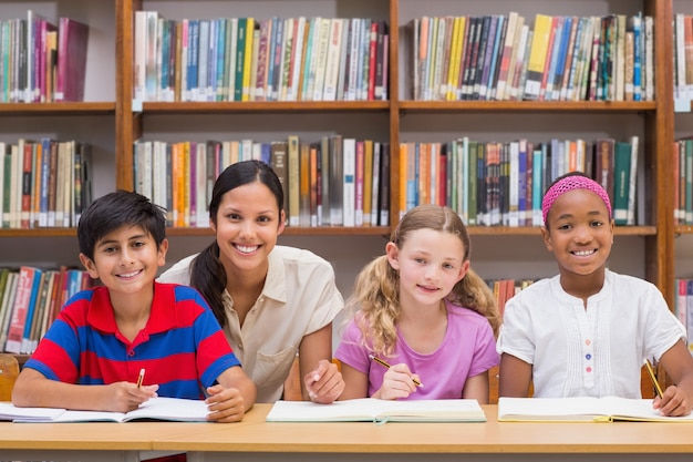 Jolie enseignante aidant les élèves de la bibliothèque