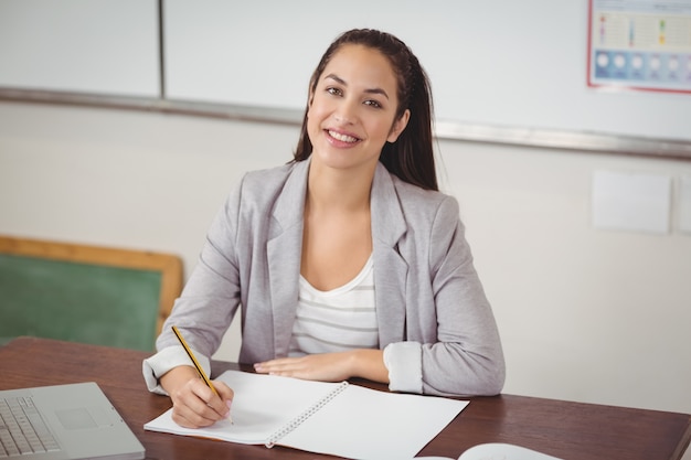 Jolie enseignante corrigeant son bureau dans une salle de classe