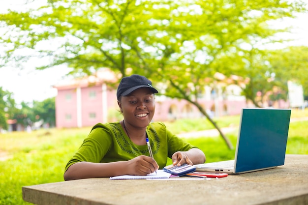 Jolie étudiante africaine se sentant excitée alors qu'elle travaille sa mission sur le campus