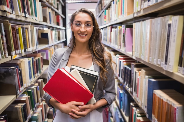 Jolie étudiante choisissant un livre dans la bibliothèque