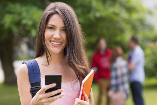 Jolie étudiante envoyant un texte à l&#39;extérieur sur le campus