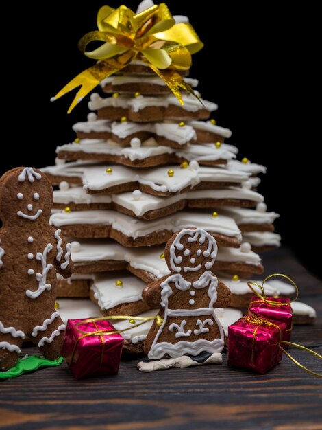 Photo jolie famille de pain d'épice près de l'arbre de noël en pain d'épice fait maison. maquette pour les offres saisonnières et la carte postale de vacances