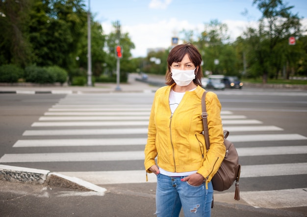 Jolie femme adulte dans des vêtements décontractés et un sac avec un masque de protection