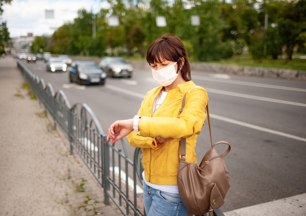 Jolie femme adulte en vêtements décontractés et sac avec un masque de protection sur son visage