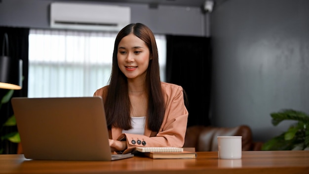 Jolie femme d'affaires asiatique travaillant dans son bureau privé à l'aide d'un ordinateur portable