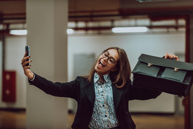 Jolie femme d'affaires en costume une mallette prenant une photo pour les réseaux sociaux avec un smartphone Mise au point sélective