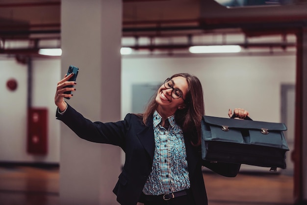 Jolie femme d'affaires en costume une mallette prenant une photo pour les réseaux sociaux avec un smartphone Mise au point sélective