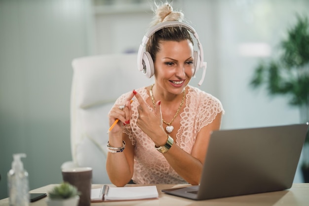 Une jolie femme d'affaires avec des écouteurs travaillant dans un centre d'appels et parlant avec un client en ligne sur son ordinateur portable.