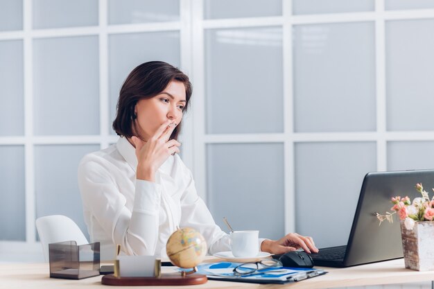 Jolie femme d'affaires fume et travaille au bureau au bureau