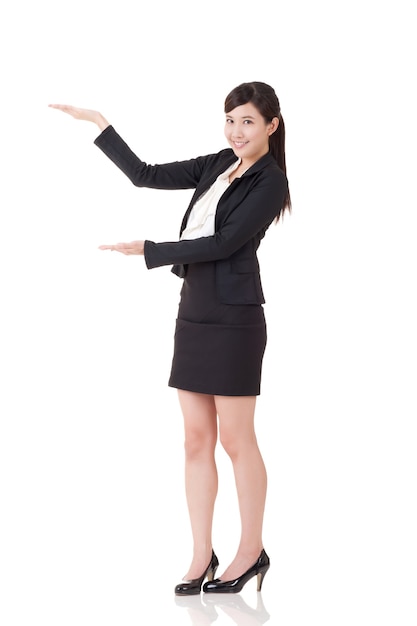 Jolie femme d'affaires introduire avec la main, portrait en pied sur fond blanc.