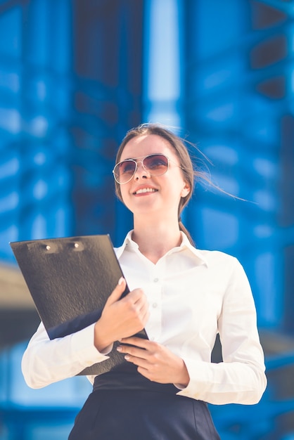 La jolie femme d'affaires en lunettes de soleil se tient avec une tablette