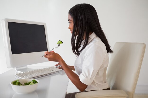 Jolie femme d&#39;affaires occasionnel, manger une salade à son bureau