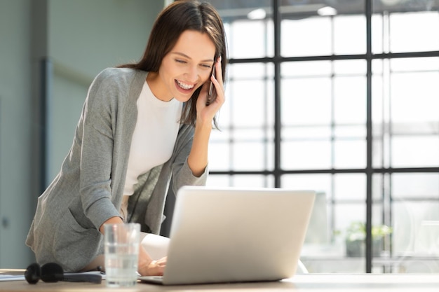 Jolie femme d'affaires parlant avec des collègues sur le téléphone portable tout en étant assis dans le bureau