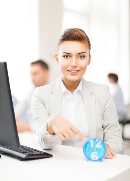 jolie femme d'affaires pointant sur l'horloge au bureau