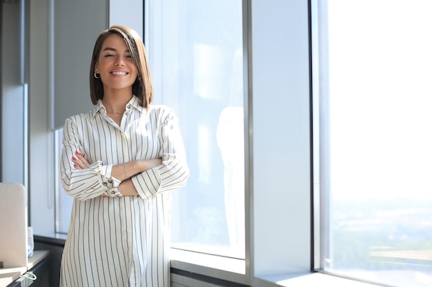 Jolie femme d'affaires regardant la caméra en se tenant debout au bureau.