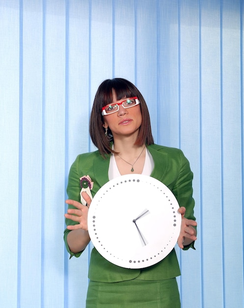 Photo .une jolie femme d'affaires se cachant derrière une horloge