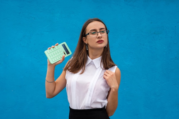 Jolie femme d'affaires tenir la calculatrice en fond bleu