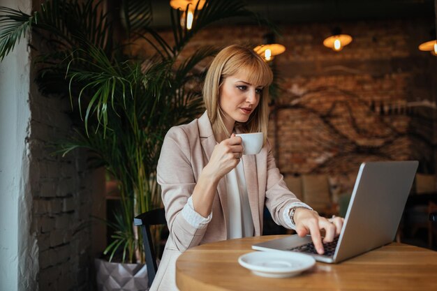 Jolie femme d'affaires travaillant sur son ordinateur portable dans un café