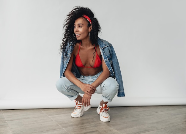 Photo jolie femme afro-américaine noire posant dans une tenue hipster élégante sur fond blanc