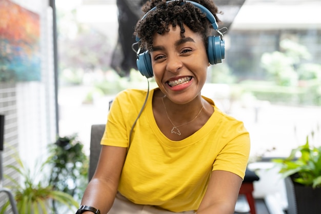 Jolie femme afro travaillant en coworking avec des écouteurs