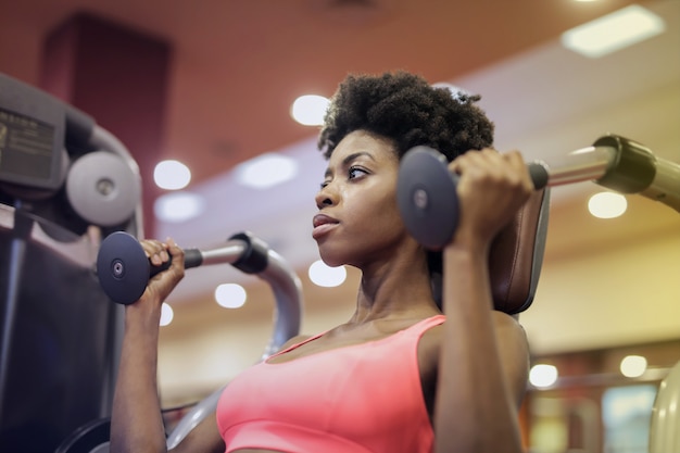 Jolie femme afro travaillant dans la salle de gym