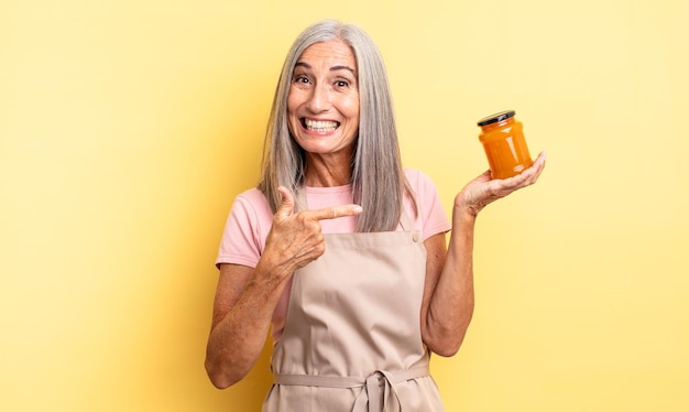 Jolie femme d'âge moyen à l'air excité et surpris en pointant sur le côté. confiture de pêche