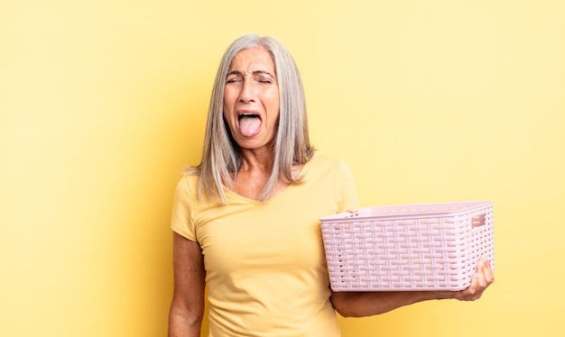 Jolie Femme D'âge Moyen Avec Une Attitude Joyeuse Et Rebelle, Plaisantant Et Tirant La Langue. Concept De Panier Vide